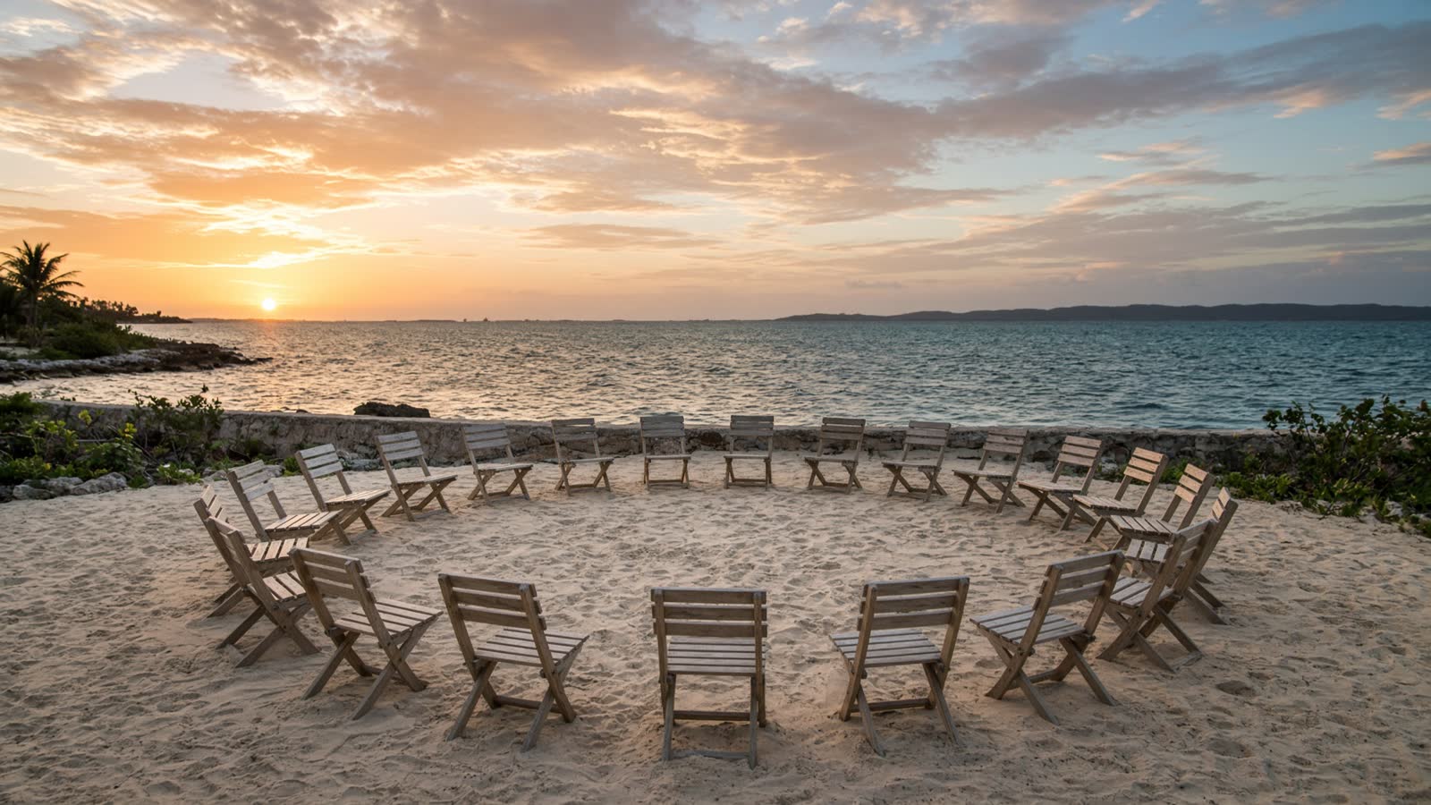 A circle of chairs facing the water at sunrise